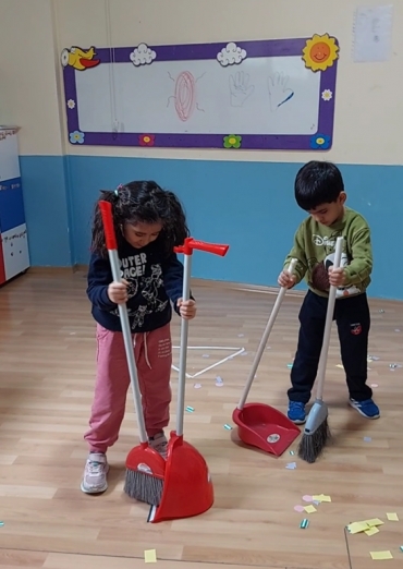 5 yaş B grubu öğrencileri Yaşam Becerileri dersinde faraş süpürge kullanarak kağıt parçalarını geometrik şekillerin içine döktüler.